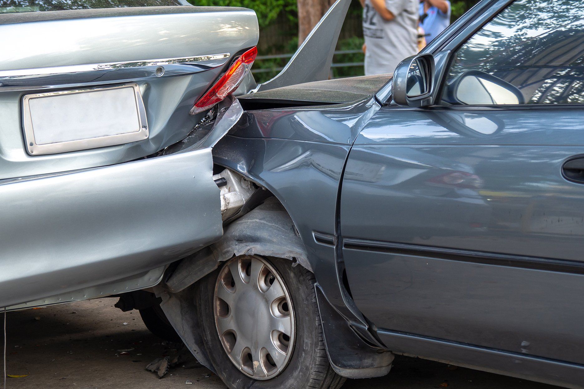 Two cars, one silver, one gray, damaged in a rear-end collision.