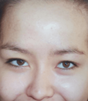 Nahaufnahme eines lächelnden Gesichts mit strahlenden Augen vor hellem Hintergrund