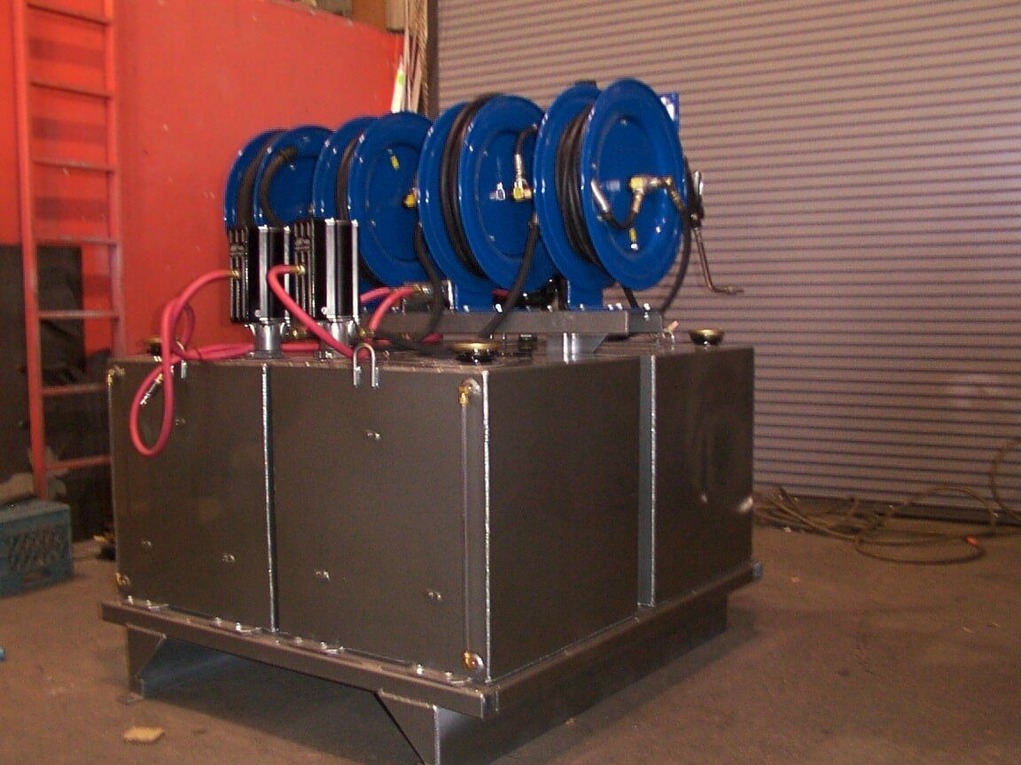 Blue hose reels atop a dark metal tank with red wiring.