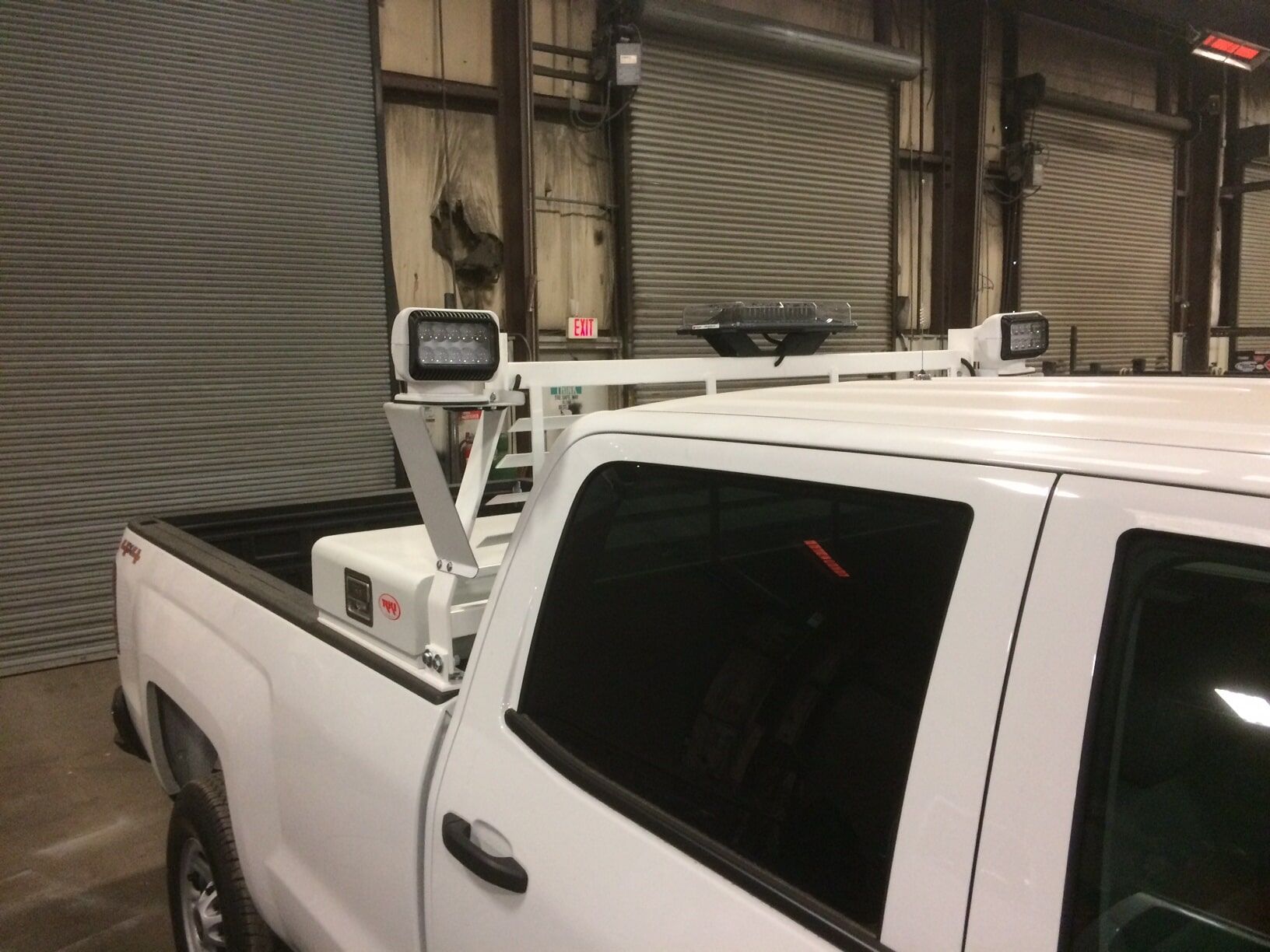 White pickup truck with equipment rack in warehouse.