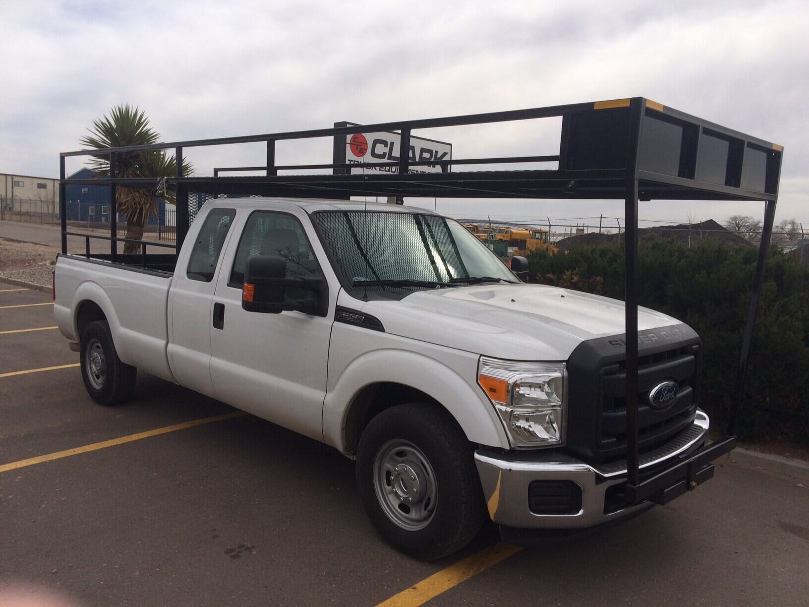 White Ford pickup truck with black overhead storage rack, parked on asphalt.