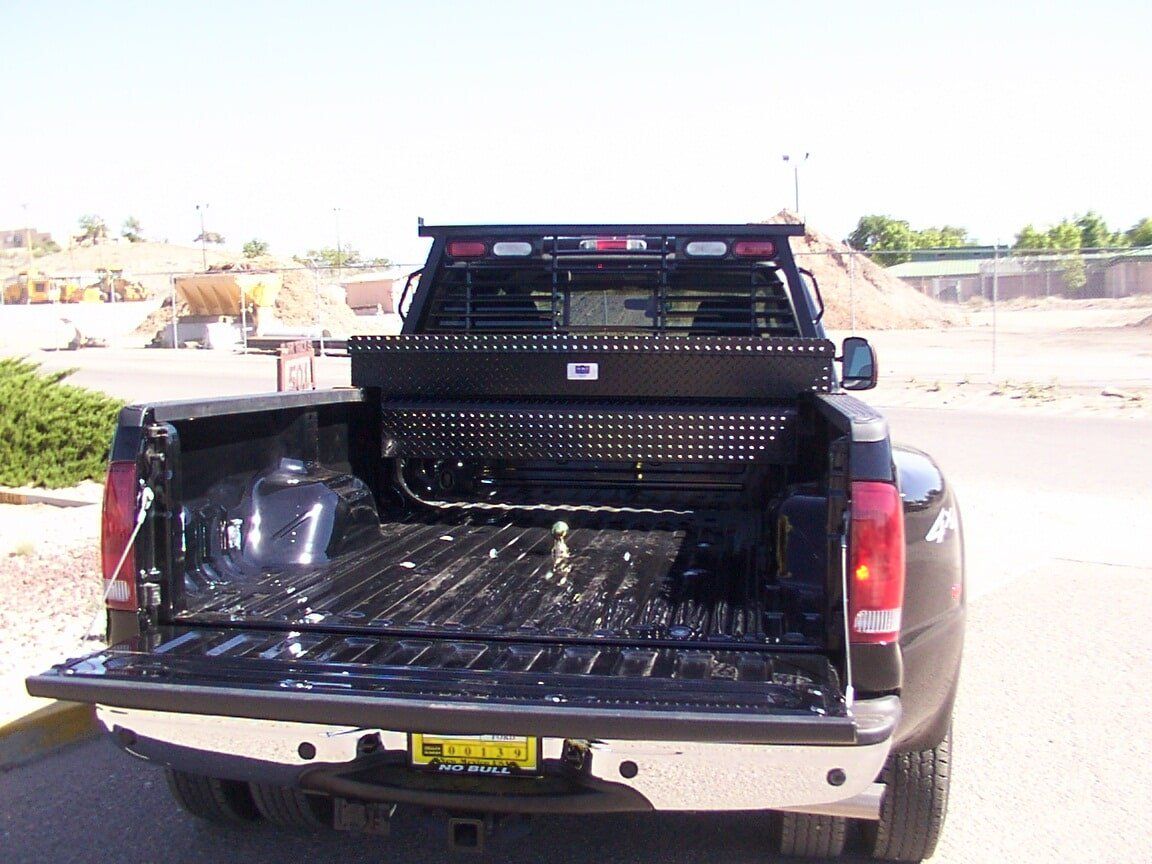 Black pickup truck bed with toolbox and cab protector, outdoors.