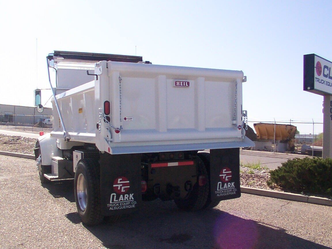 White dump truck with black fenders parked outdoors.