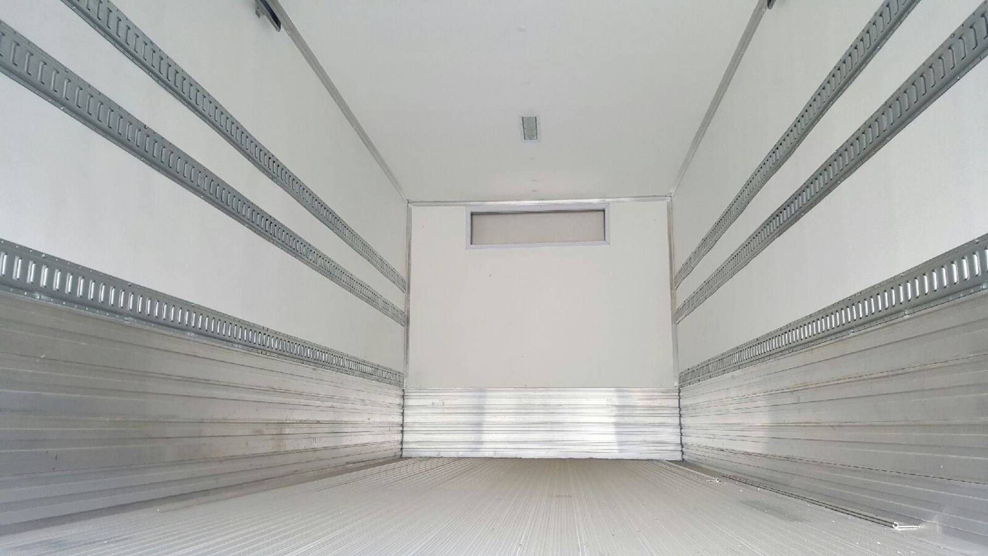 Empty refrigerated truck interior with white walls and metal tracks.