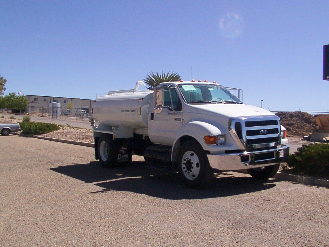 White water tanker truck parked outside on a sunny day.
