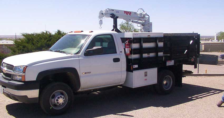 White Chevrolet truck with a crane, parked outdoors.