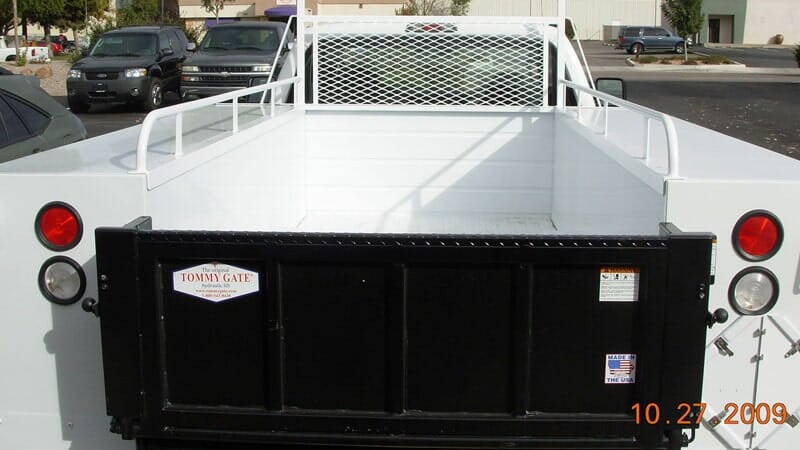 White flatbed truck bed with black tailgate.