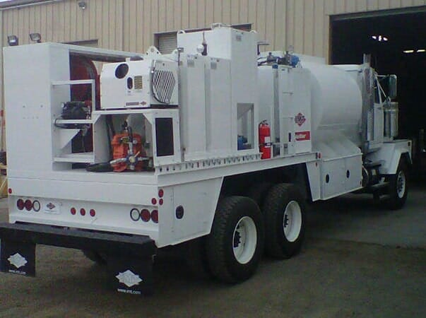 White tanker truck parked outside a building; rear view.