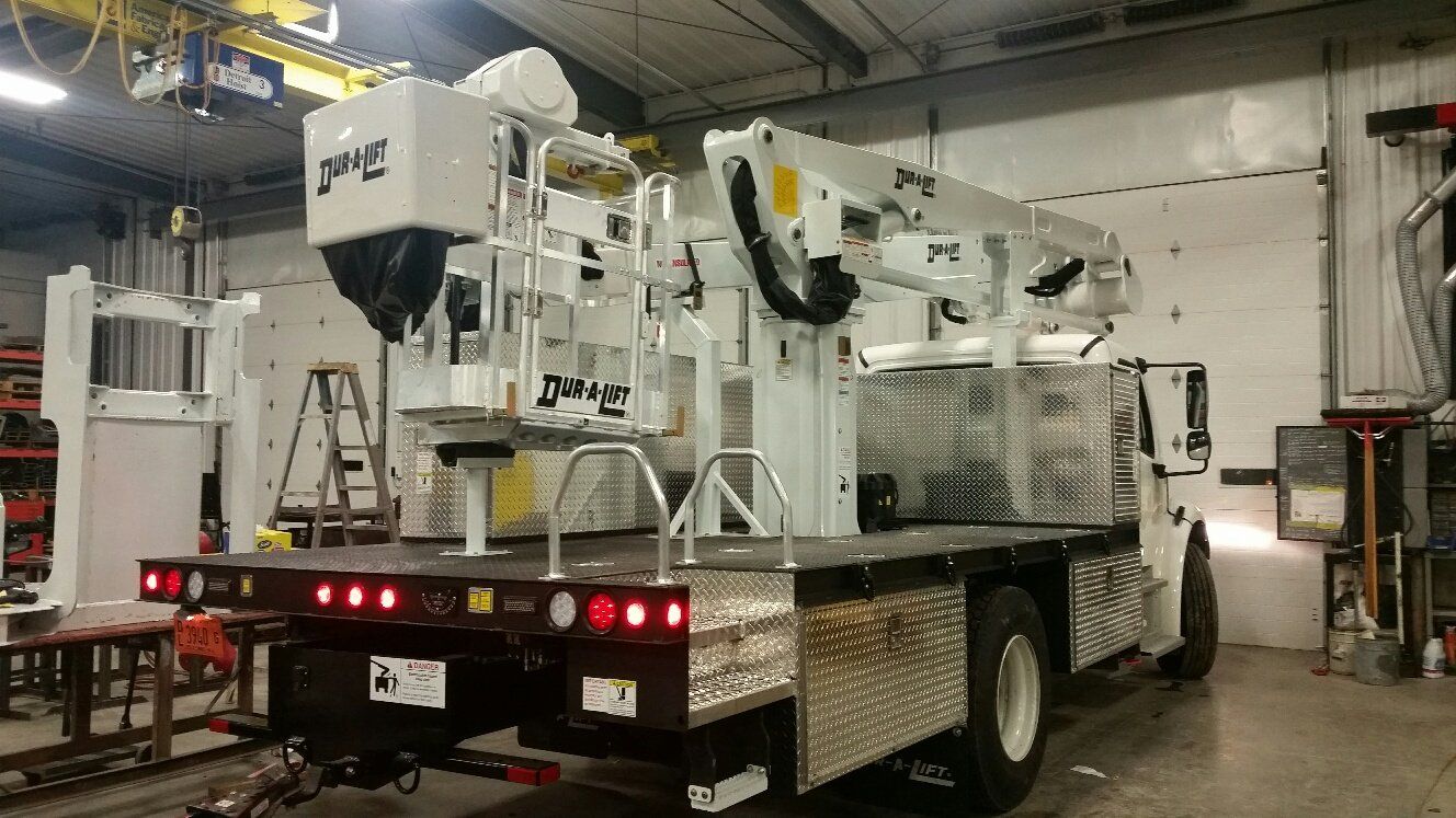 White utility truck with a boom lift in a shop.
