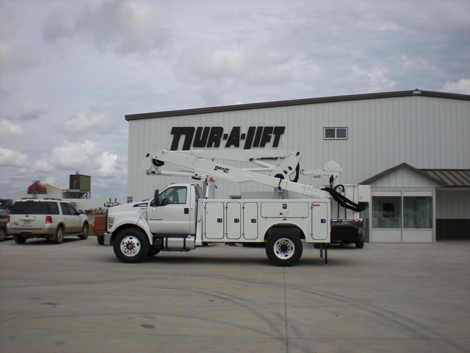 White bucket truck parked in front of a building with 
