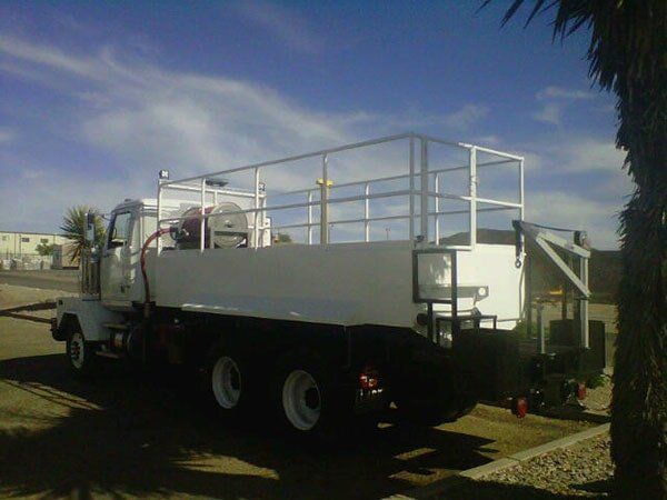White water truck parked outdoors on a sunny day. It has a large white tank and safety rails.