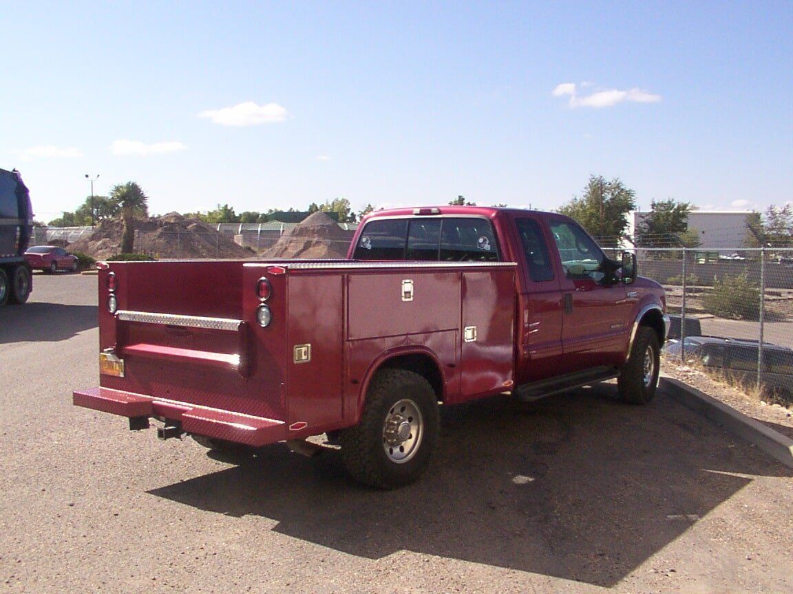 Red work truck with toolboxes parked outdoors.