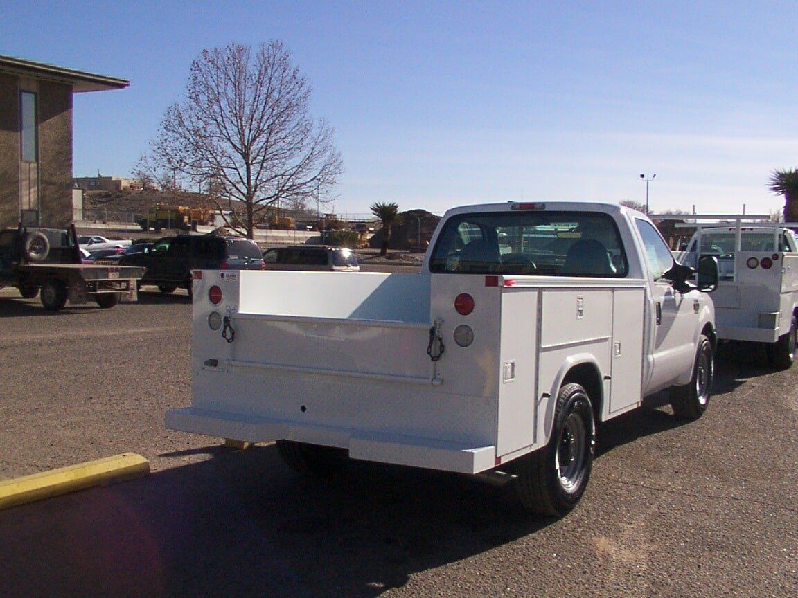 White work truck parked on a sunny day, with a large flat bed.