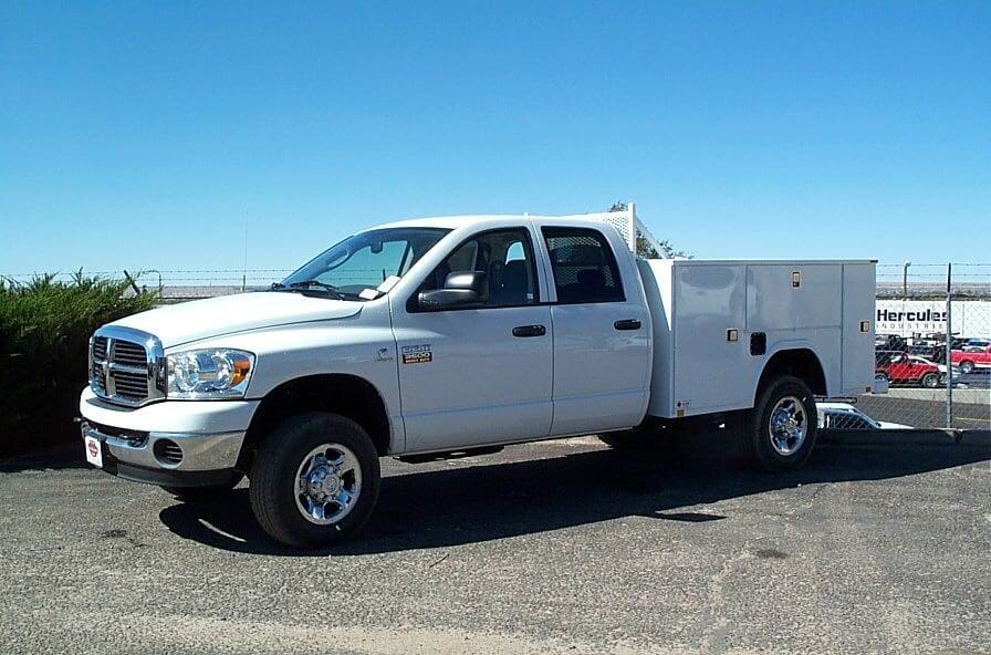 White Dodge Ram service truck on a sunny day, parked on pavement.