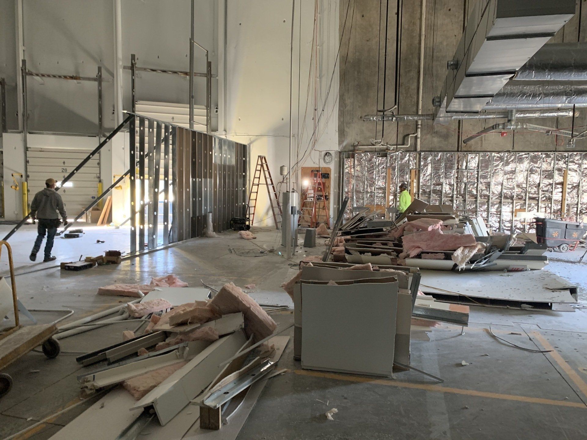 Construction workers inside a partially finished building with debris, scaffolding, and exposed walls.
