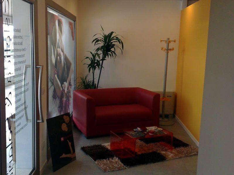 A comfortable waiting room with a colourful rug, a red sofa, and plants
