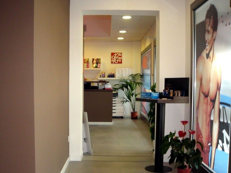 An access corridor to the reception, featuring a poster of a young tan and a high table with various products
