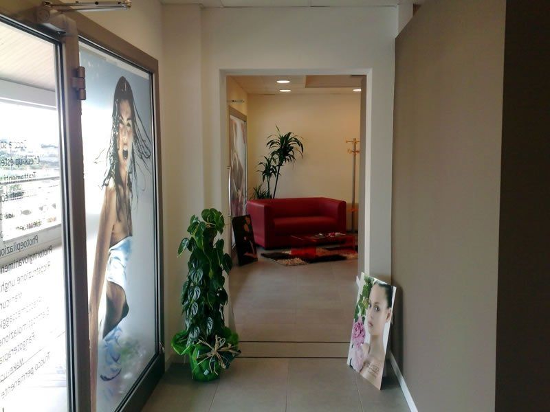 An access corridor to the waiting room, featuring a poster of a young tanned person, with plants adding a natural touch