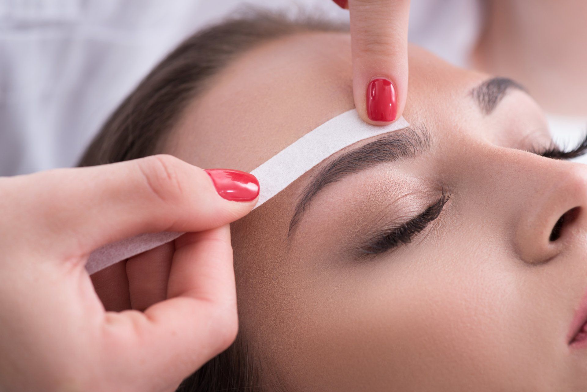 A woman is getting her eyebrows waxed in a beauty salon.