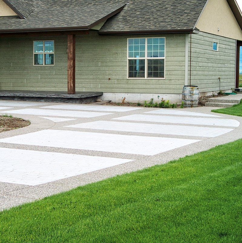 A green house with a white driveway in front of it