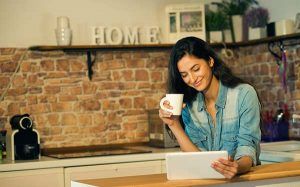 Woman drinking coffee and reading tablet