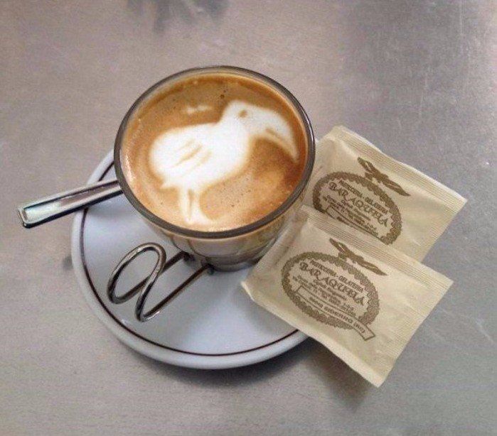 una tazza di cappuccino e accanto due bustine di zucchero
