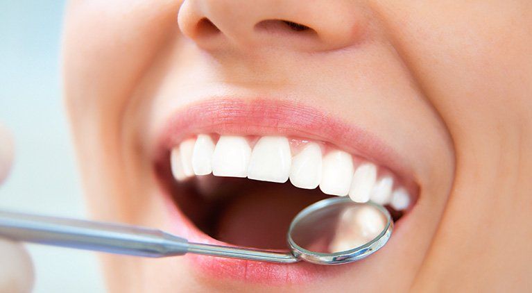 dentist looking with a mirror inside a womans mouth