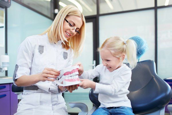 dentist showing girl teeth model