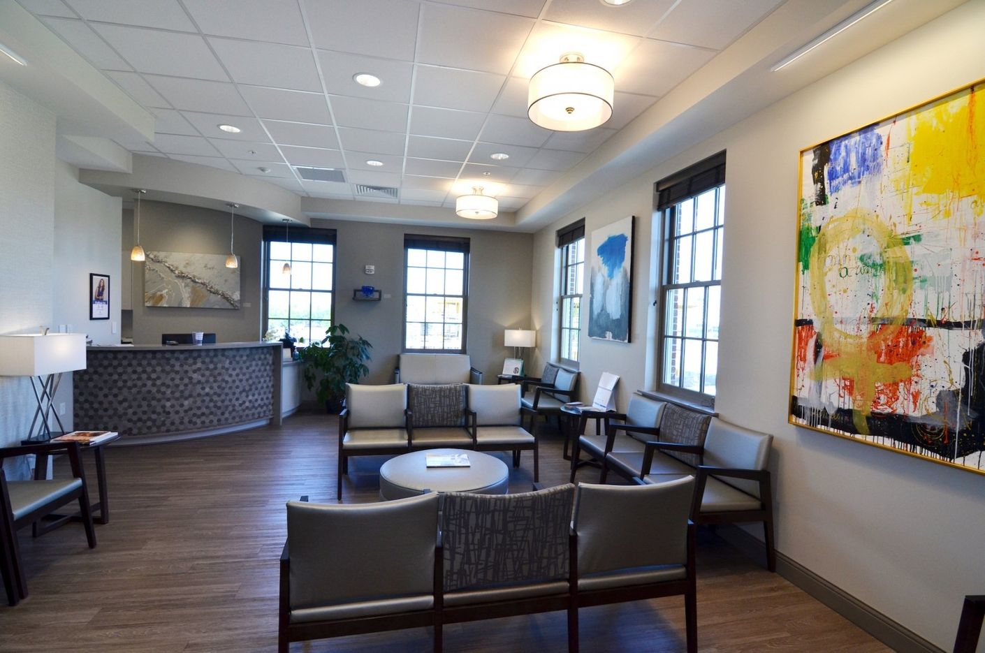 A waiting room with a couch and chairs and a painting on the wall.
