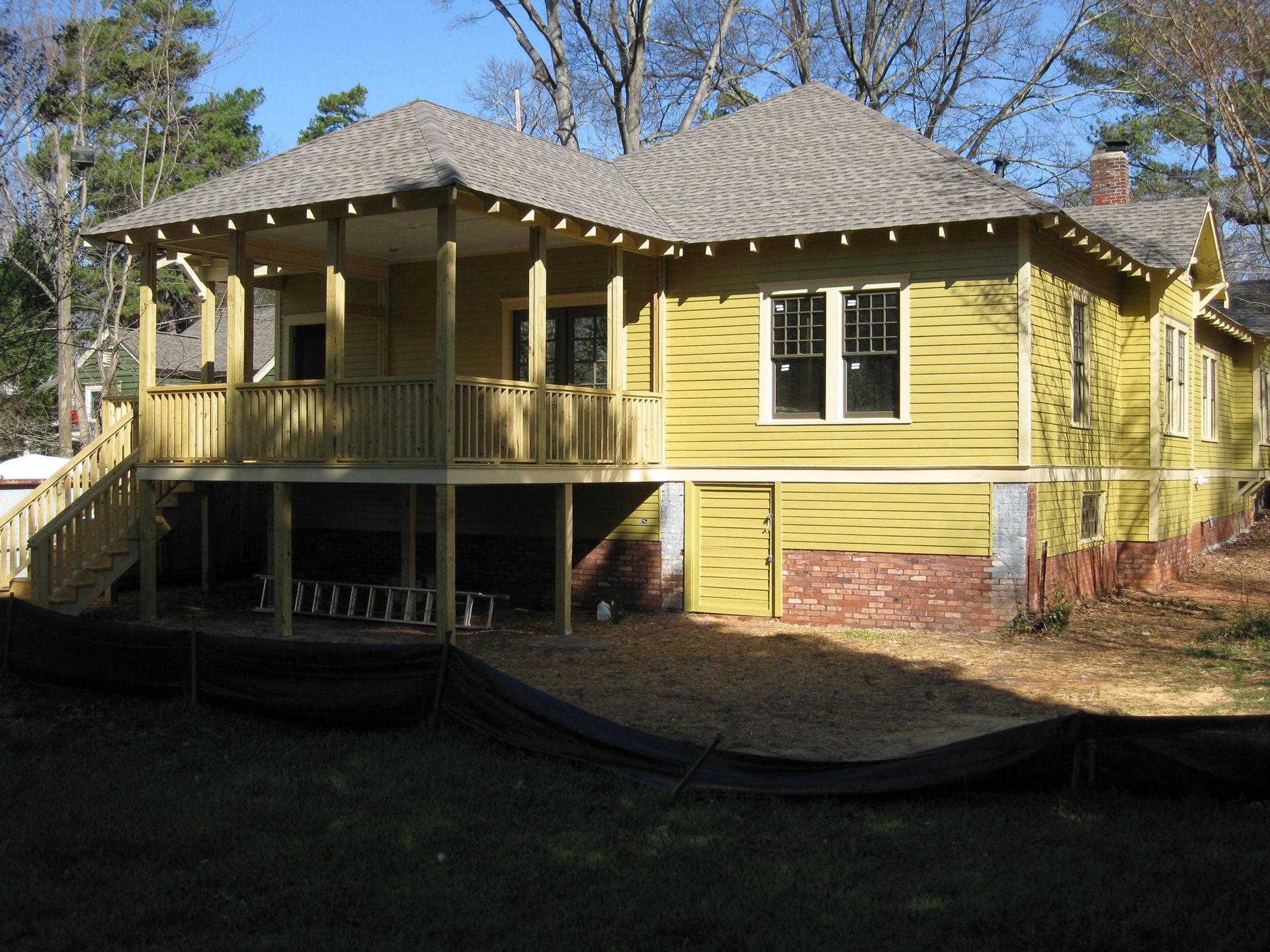 A yellow house with a large porch and stairs