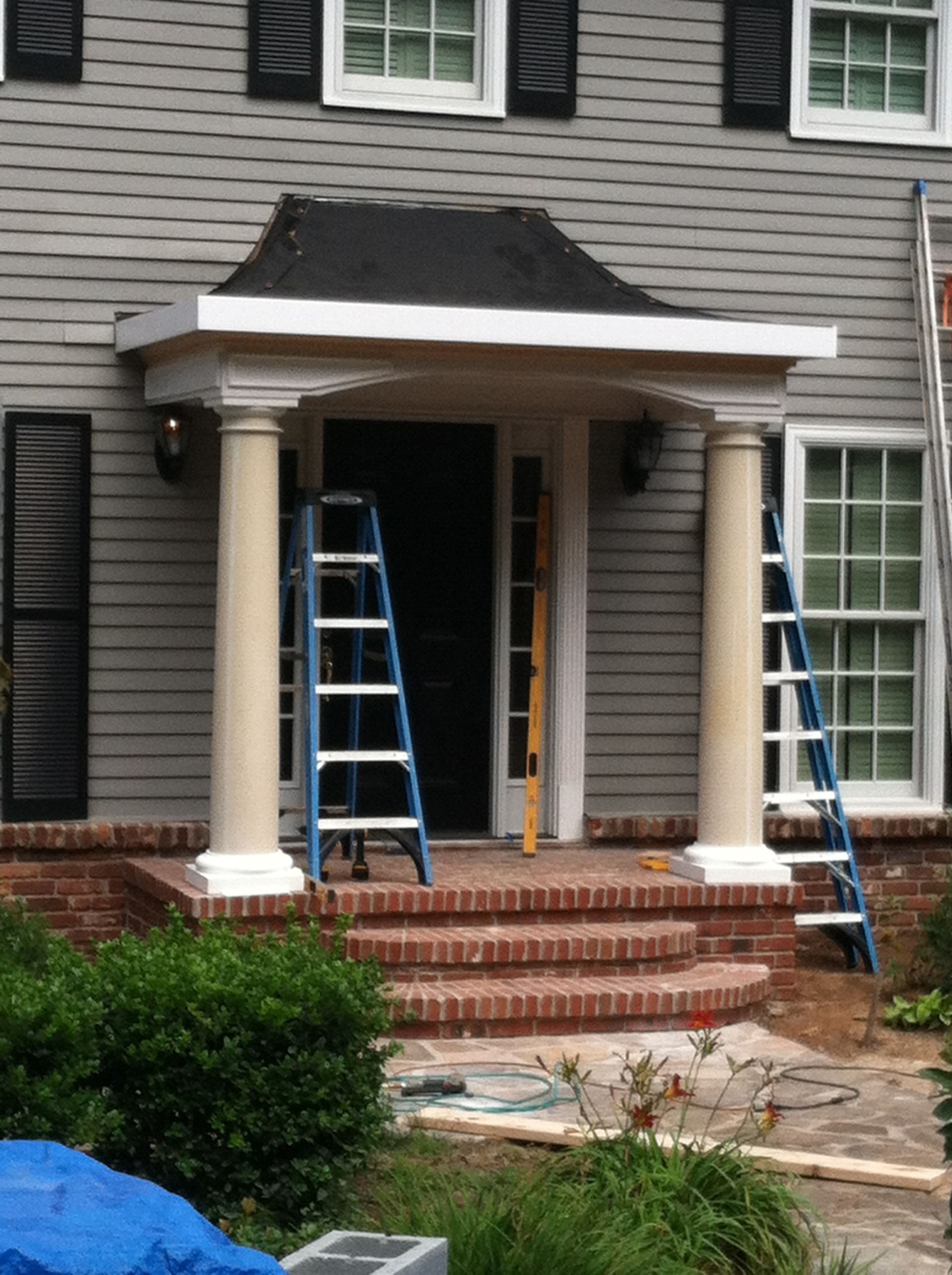 A house with a porch and a ladder in front of it