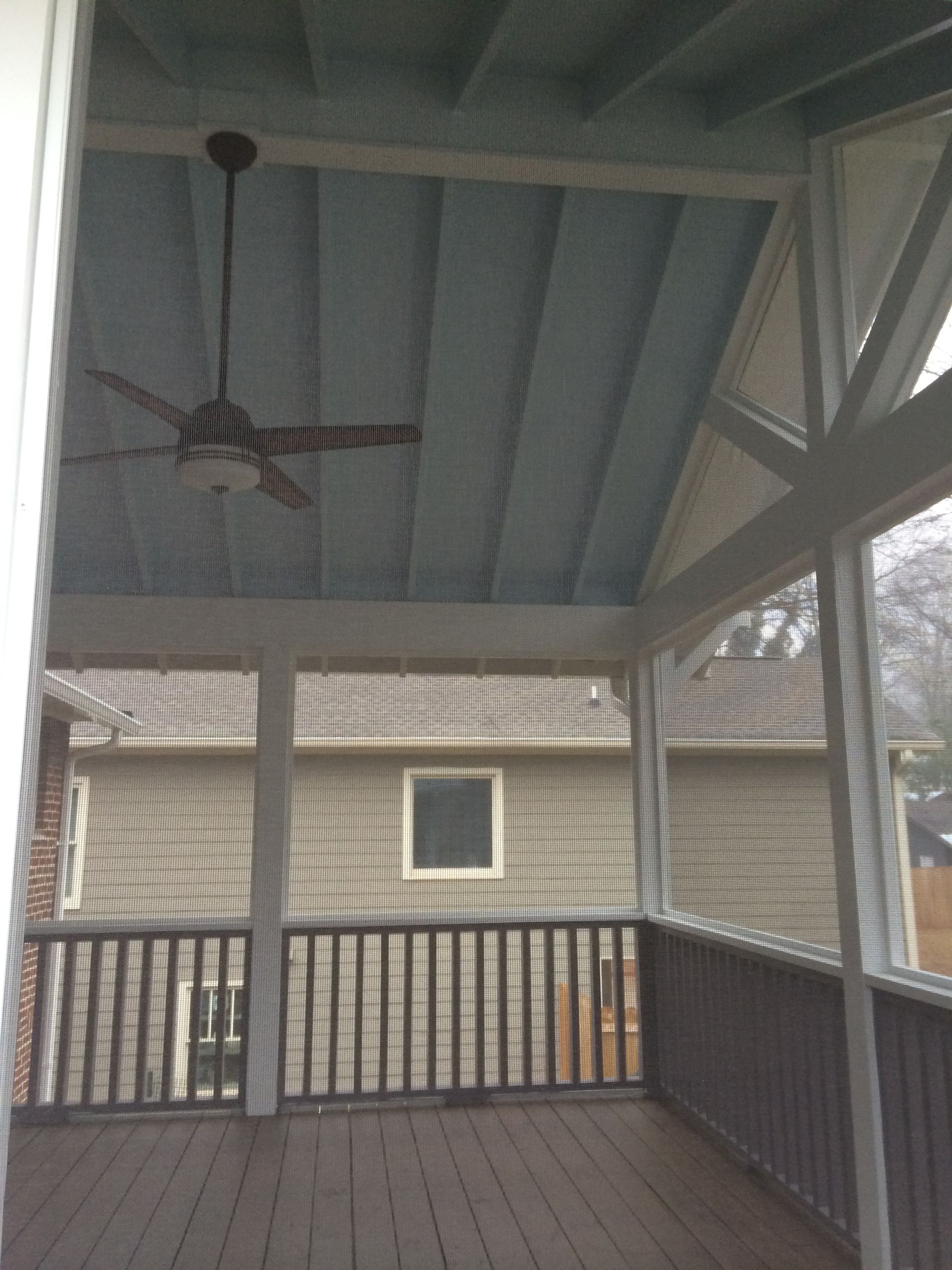 A screened in porch with a ceiling fan