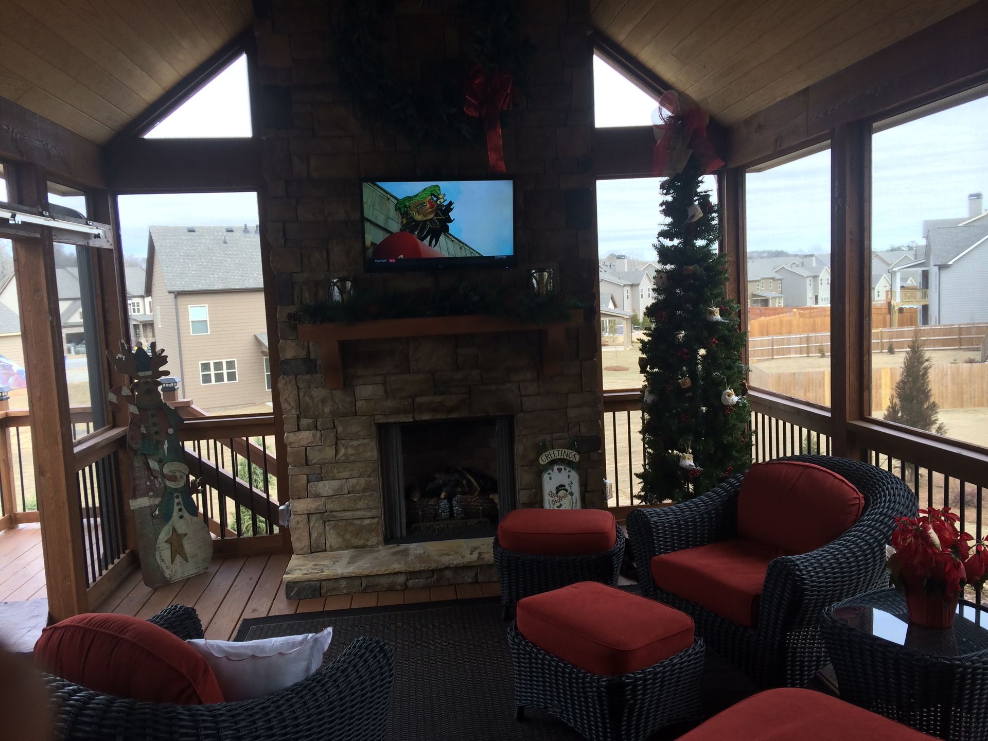 A screened in porch with a fireplace and a television