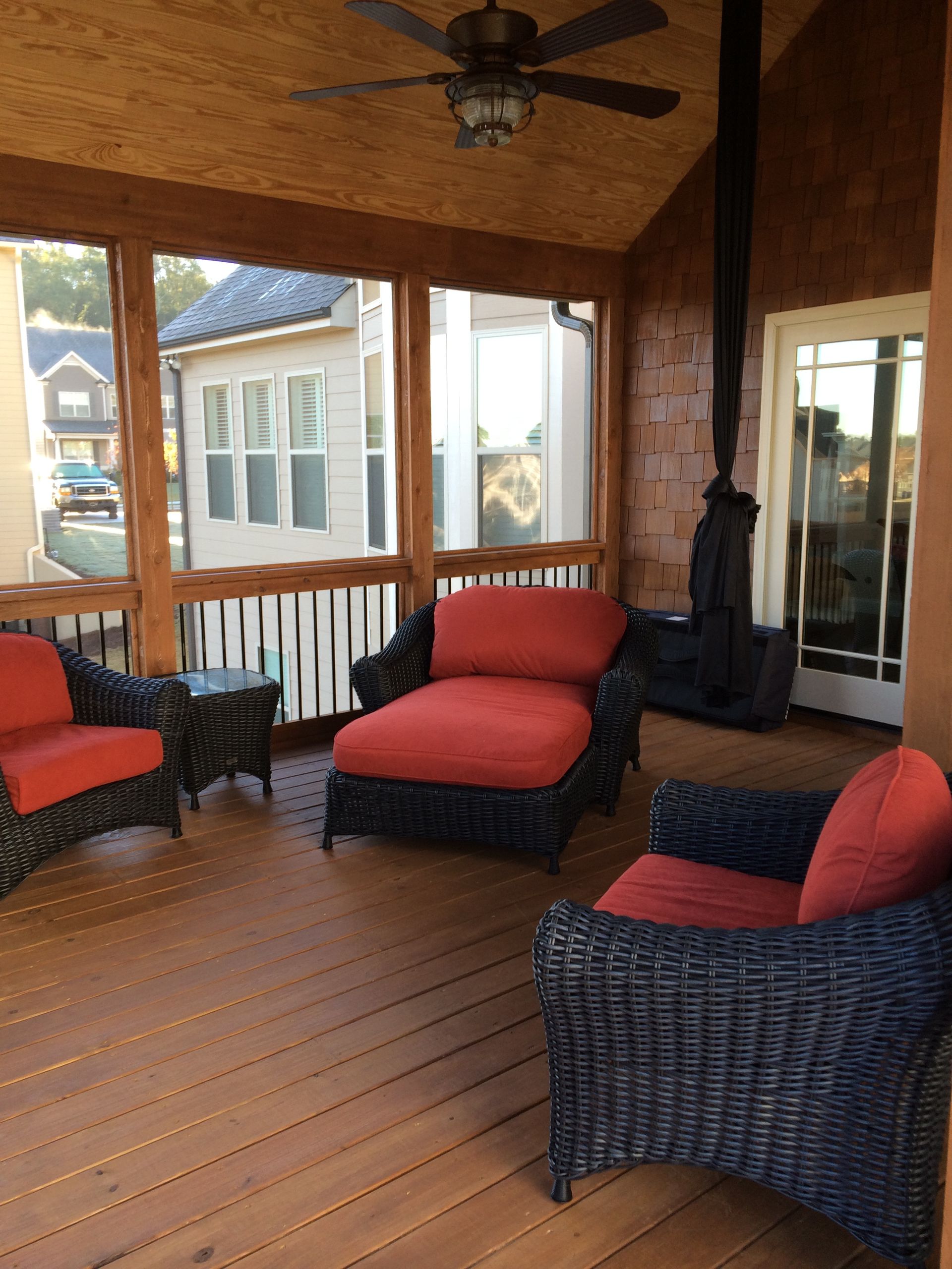 A screened in porch with wicker furniture and a ceiling fan