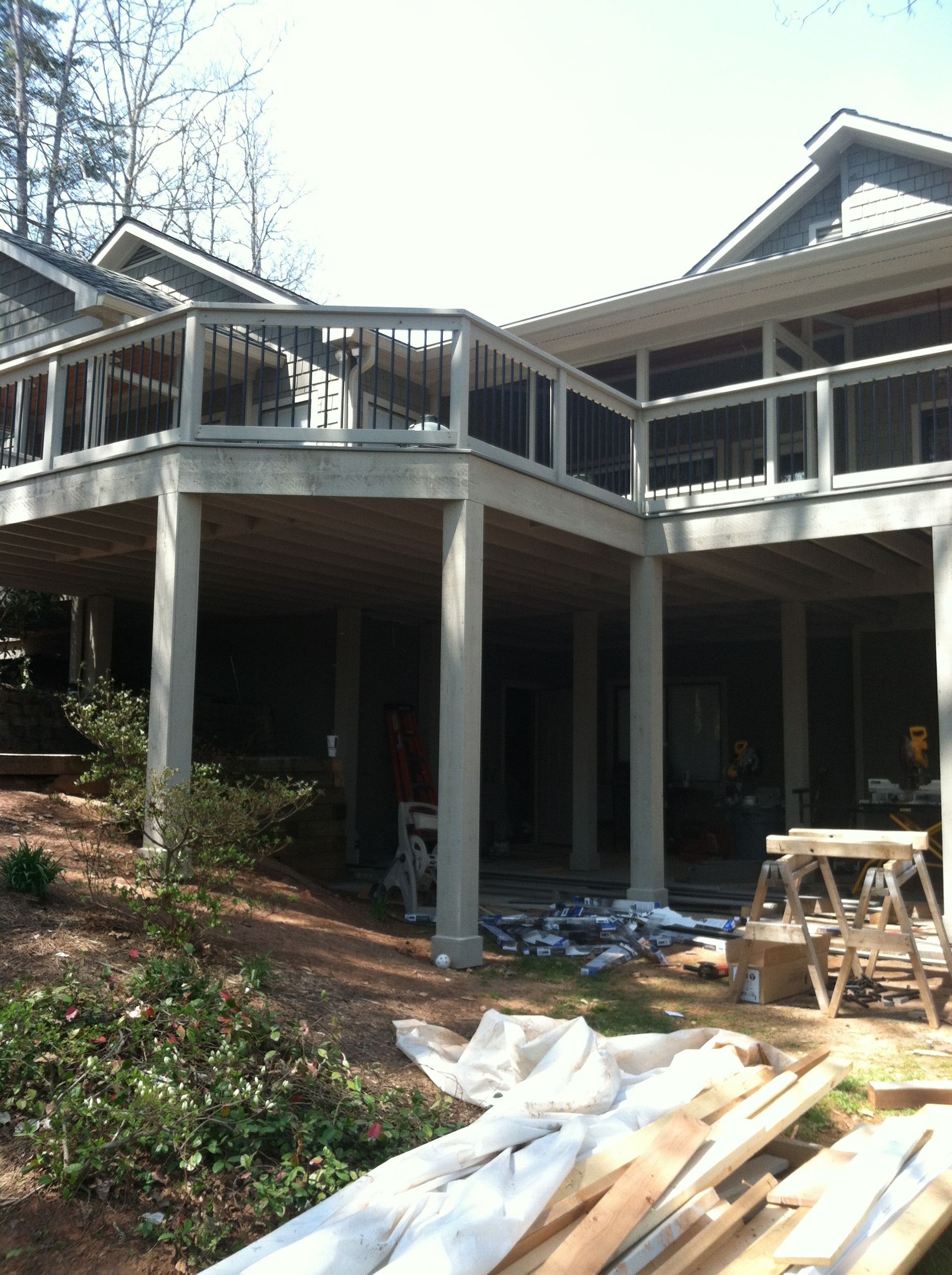 A house with a large deck and a stack of wood in front of it