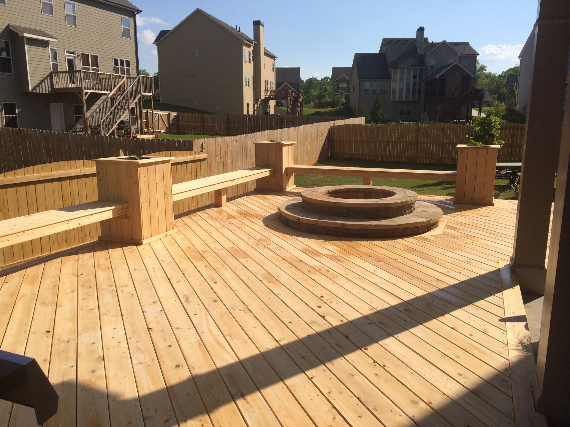 A wooden deck with a fire pit and benches