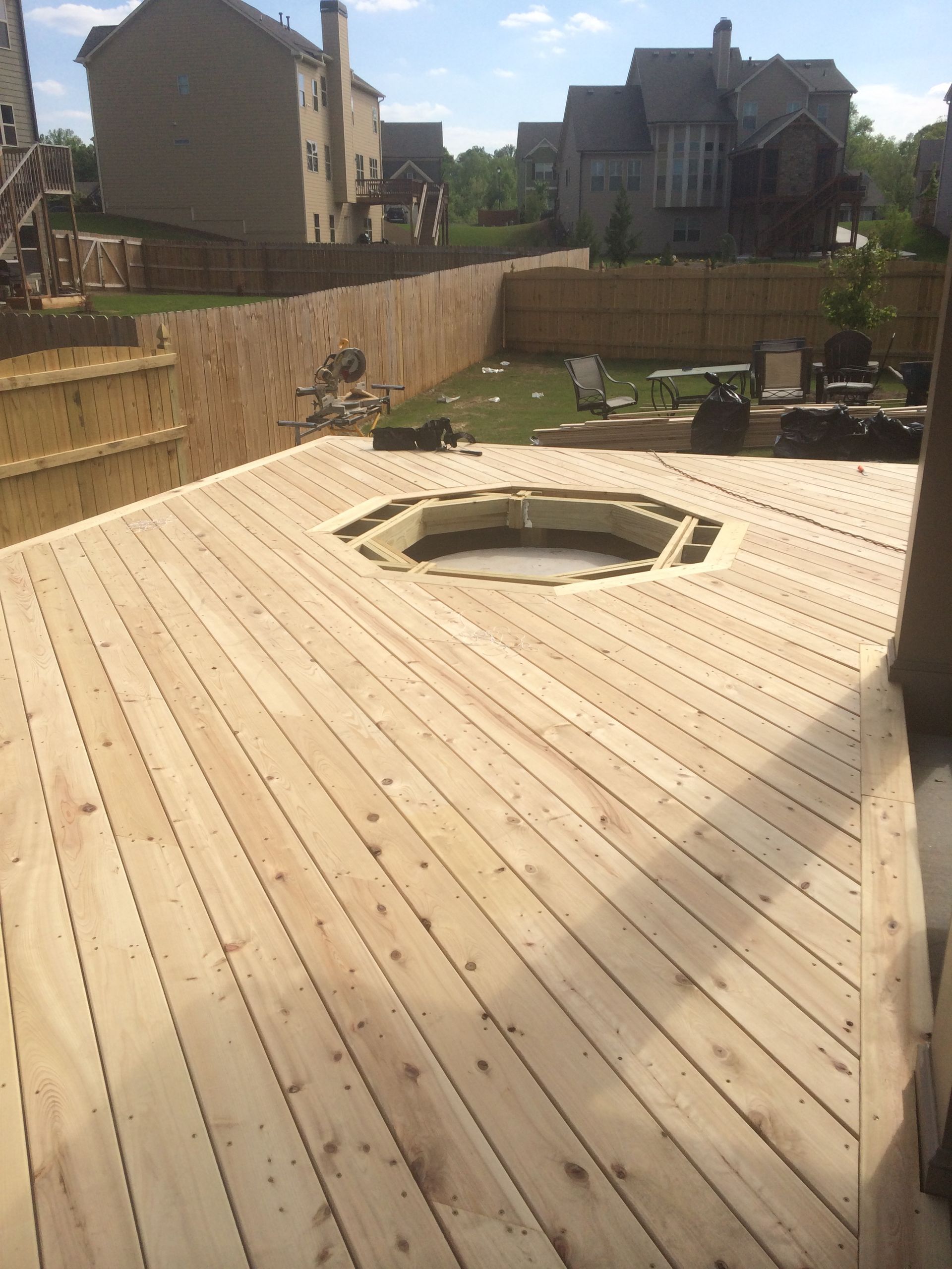 A wooden deck with a fire pit in the middle of it