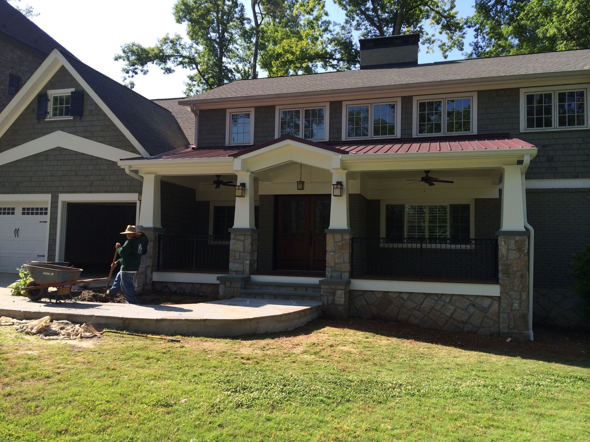 A man is standing in front of a house with a large porch