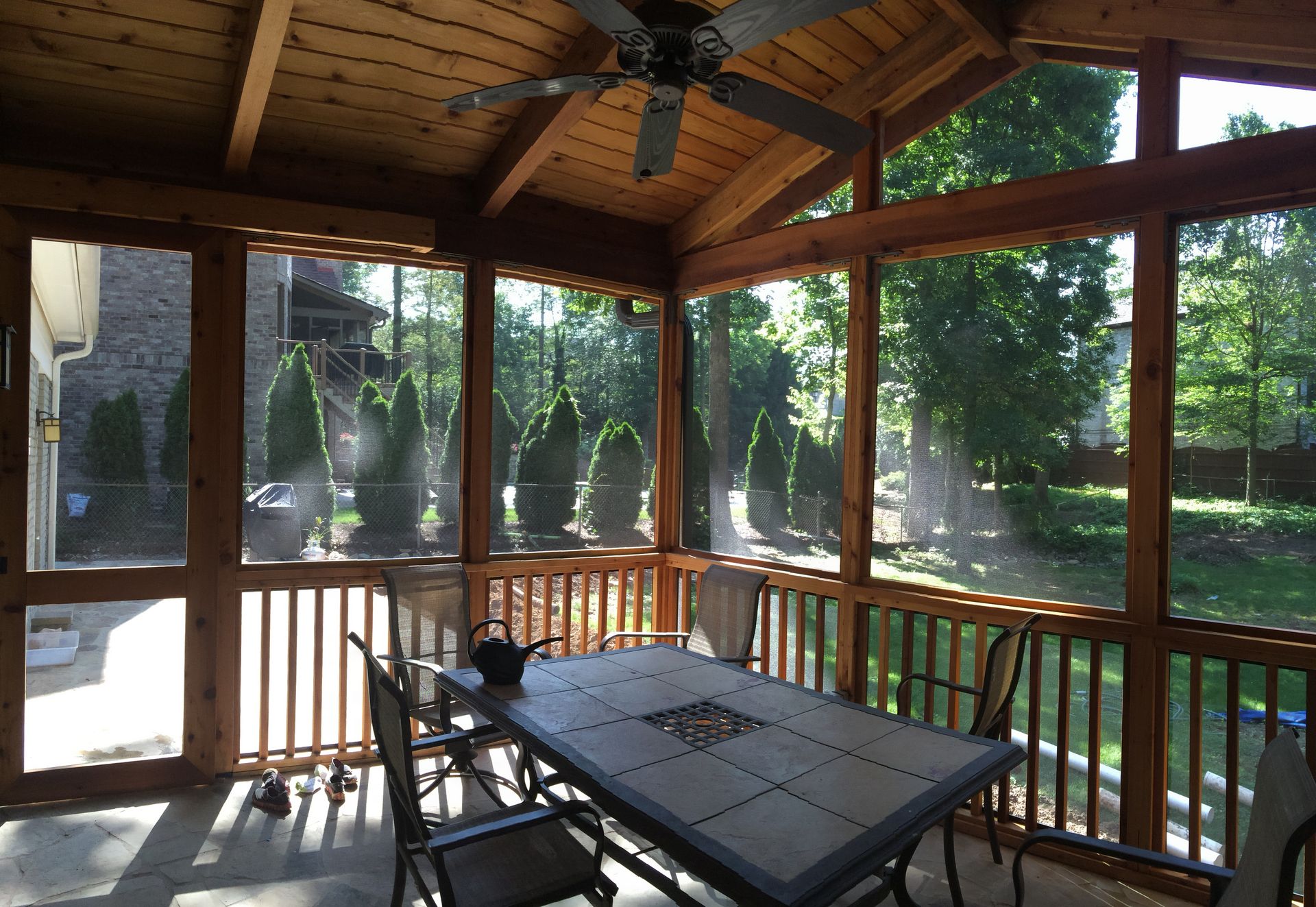 A screened in porch with a table and chairs and a ceiling fan