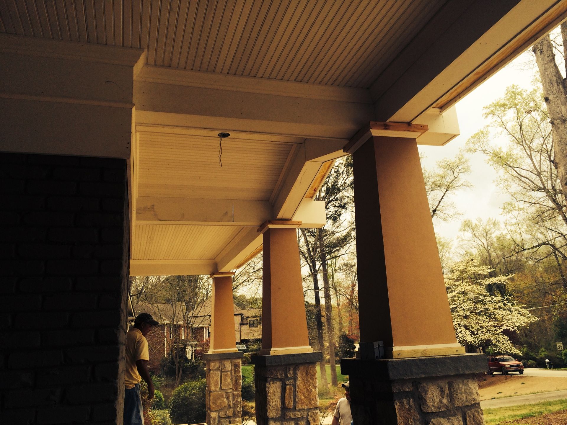 A man is standing under a porch with columns