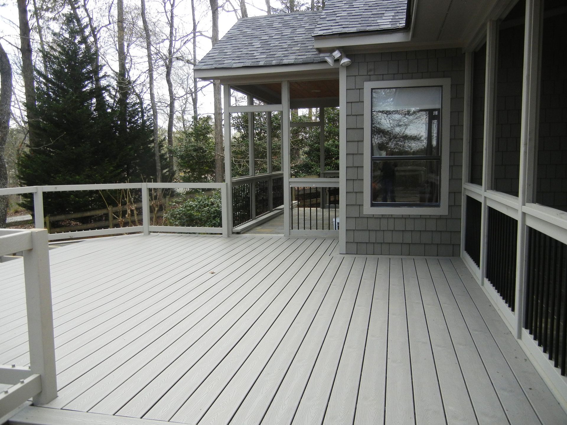 A screened in porch with a gray house in the background