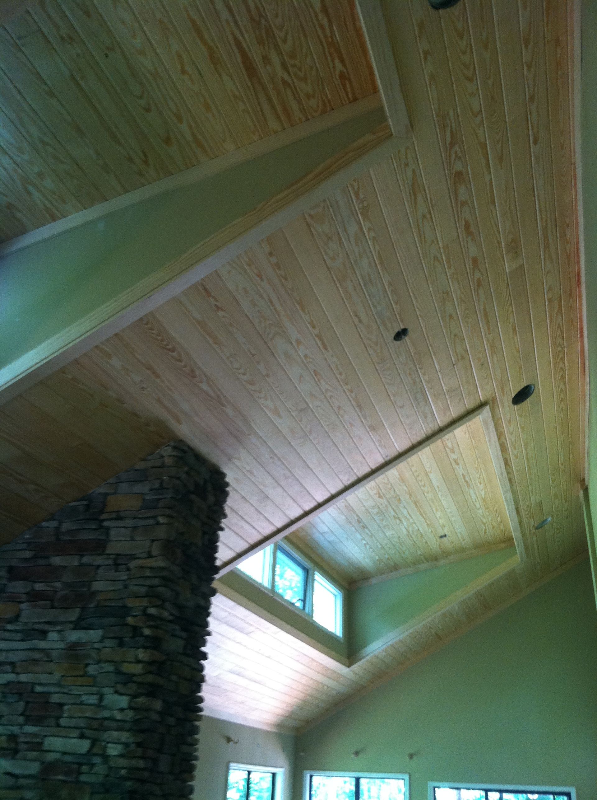 A living room with a wooden ceiling and a stone fireplace.