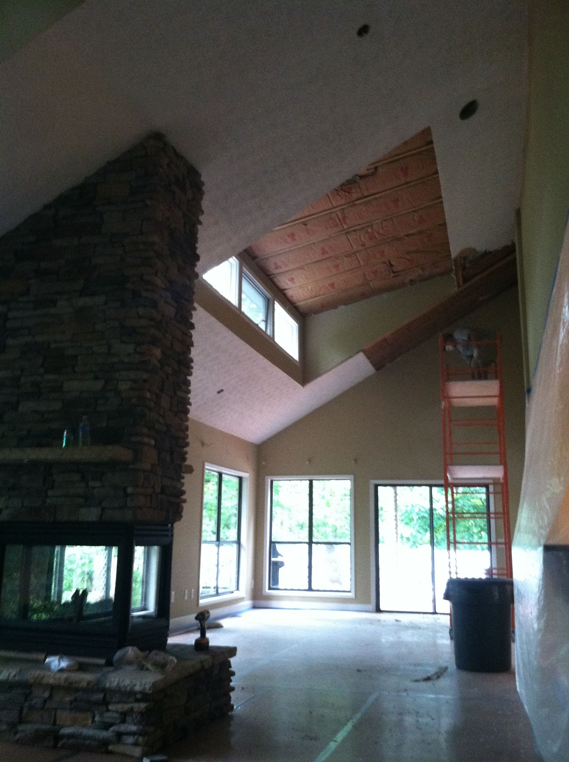 A living room with a large stone fireplace and lots of windows