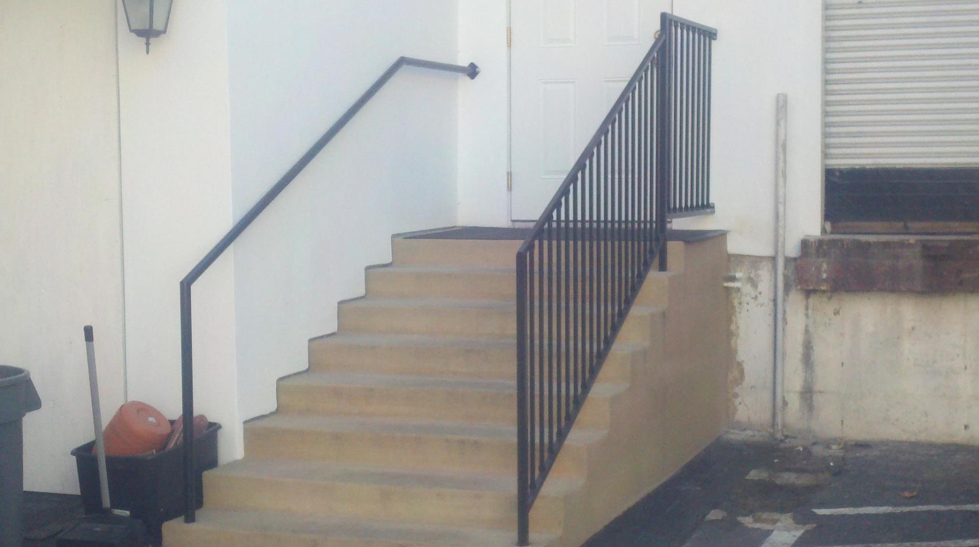 Outdoor concrete stairs with black metal handrails.