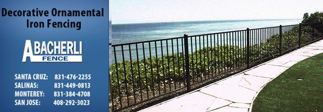Black iron fence along the ocean with company logo and contact info on left.