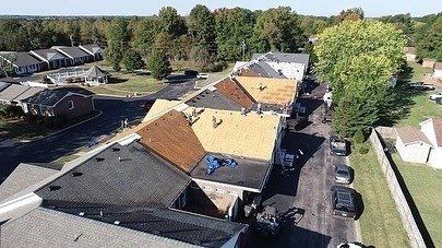 Aerial view of apartment rooftops with parking lot and trees in a residential complex