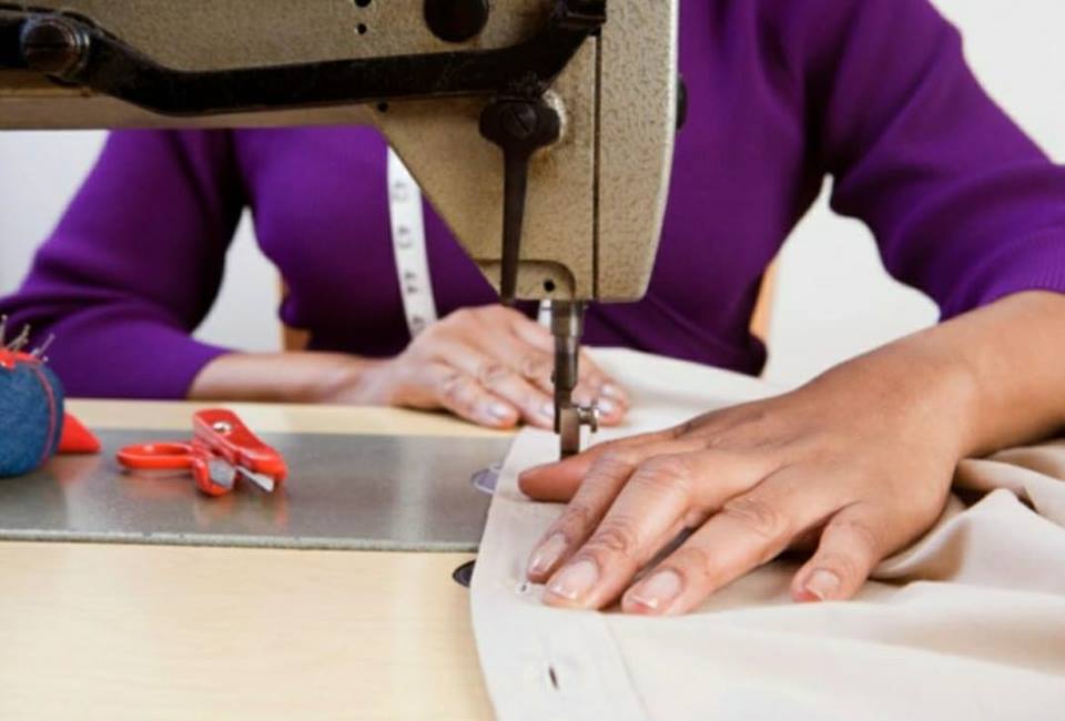 A woman in a purple shirt is using a sewing machine