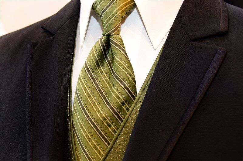 A man wearing a black suit and a green tie