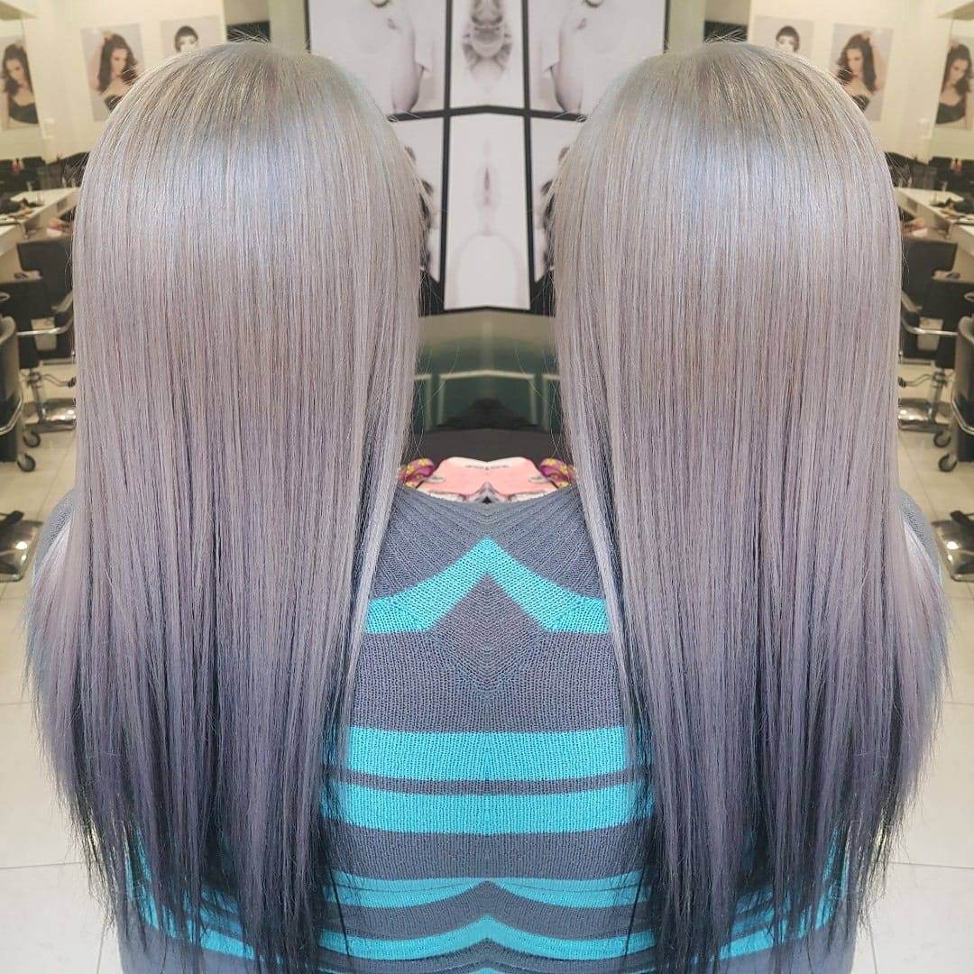 A woman with long gray hair is sitting in a chair in a salon.