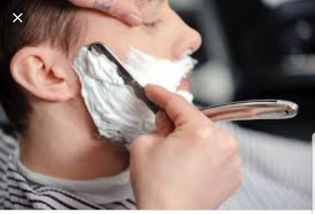 A man is getting his beard shaved by a barber.